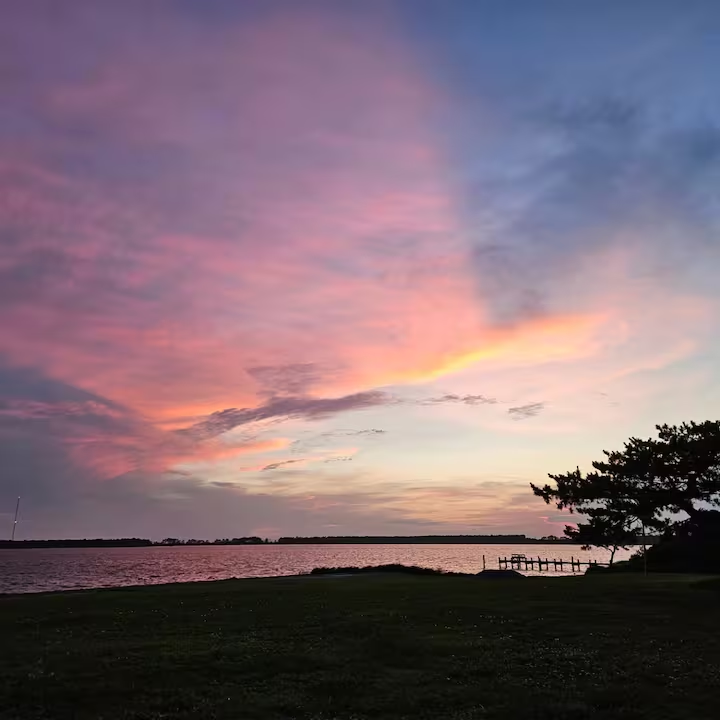 Pink and gold sunset over Nelson’s Bay, with the Sea Level shoreline in silhouette